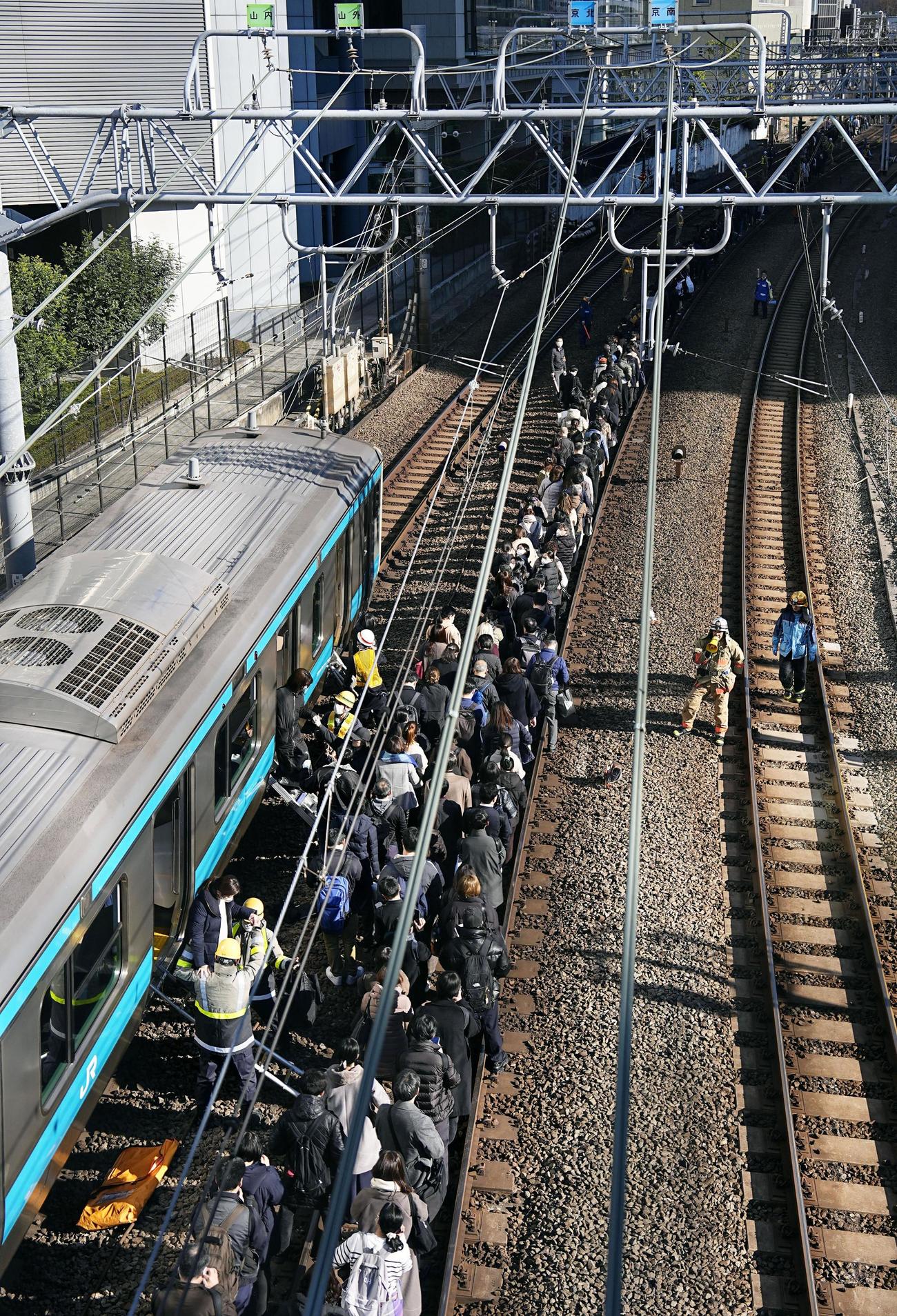 高輪ゲートウェイ－田町間で停車したJR京浜東北線の車両から降りて線路を歩く乗客（共同）