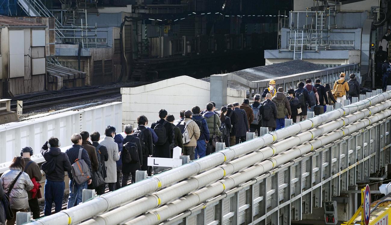 新橋－浜松町間で停車したJR京浜東北線の車両から降りて線路を歩く乗客（共同）