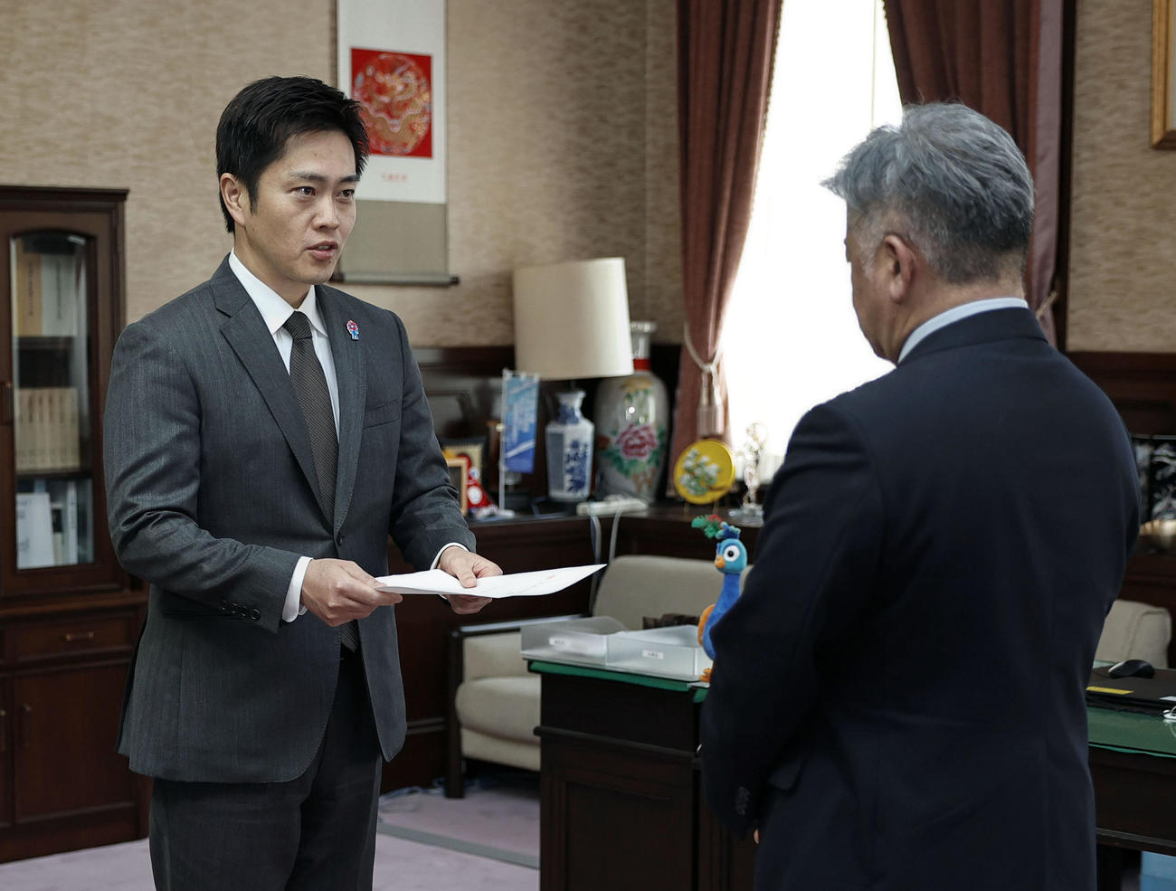 大阪府議会の金城克典議長（右）に辞職願を提出する吉村洋文知事（共同）