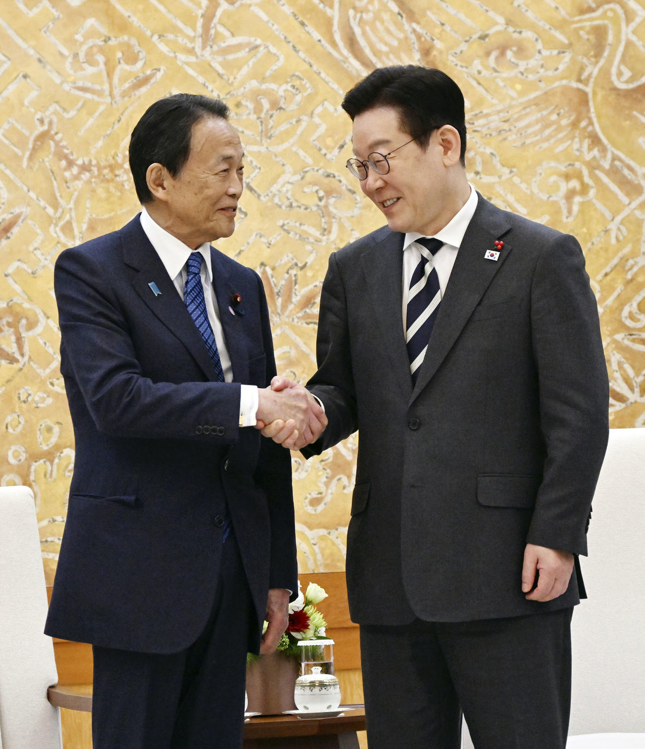 韓国の李在明大統領（右）と握手を交わす自民党の麻生副総裁＝16日、韓国大統領府（共同）
