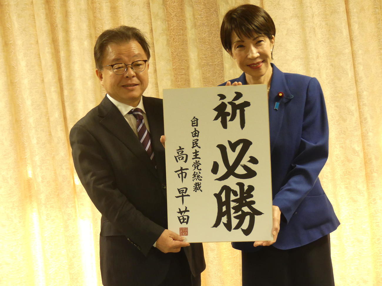 福井県知事選の告示前に「祈　必勝」の色紙を山田賢一氏（左）に手渡す高市早苗・自民党総裁（2026年1月撮影）