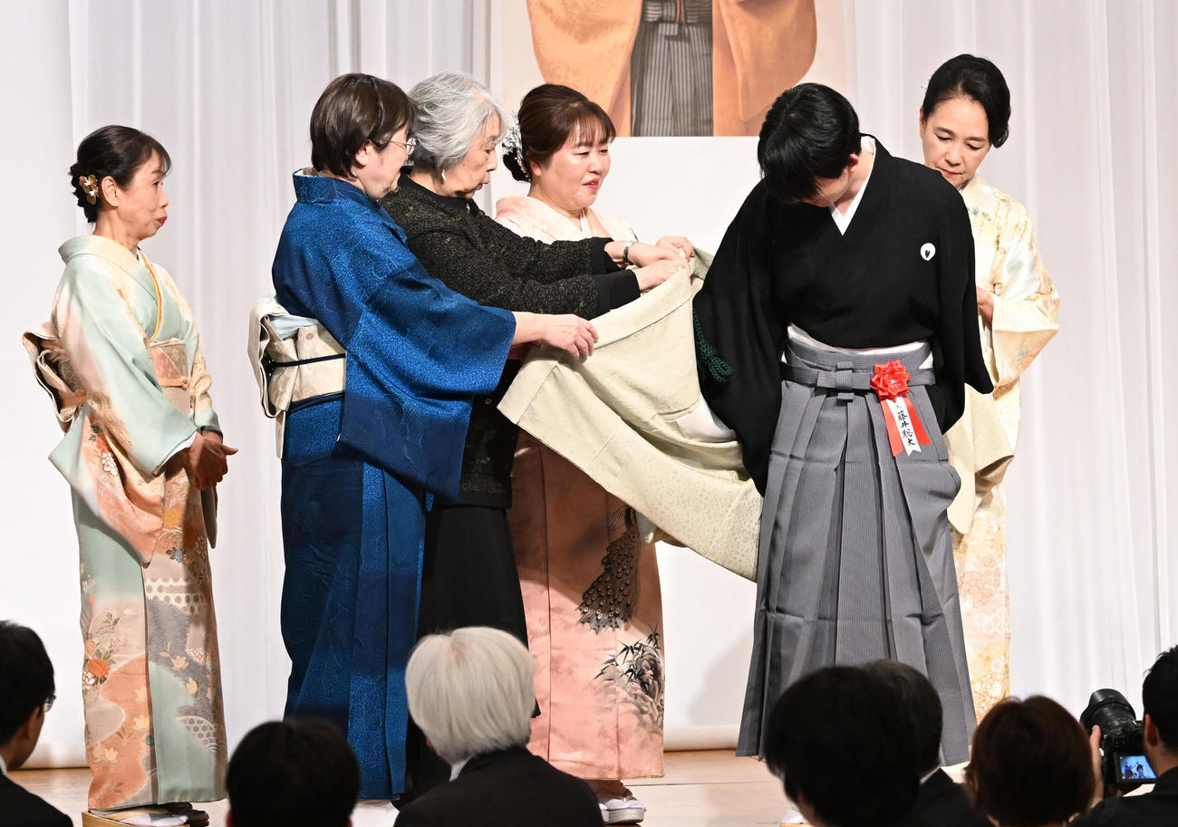 第38期竜王就位式　クラウドファンディングの支援者に贈られた記念の羽織を着せてもらう藤井竜王（撮影・千葉一成）