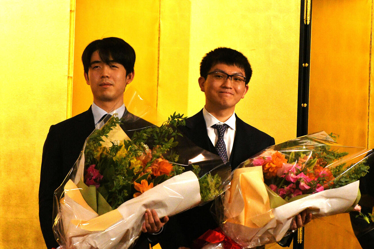 立川市で行われる王将戦第3局の前夜祭で花束を手にする藤井聡太王将（左）と永瀬拓矢九段（右）
