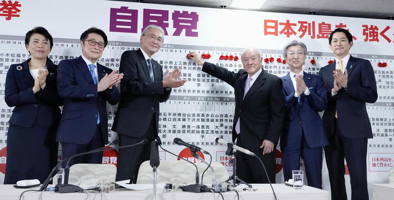 当確者の名前にバラを付ける自民党の鈴木幹事長（中央右）と、拍手する、左から有村総務会長、松山参院議員会長、古屋選対委員長、1人おいて石井参院幹事長、小林政調会長(共同)