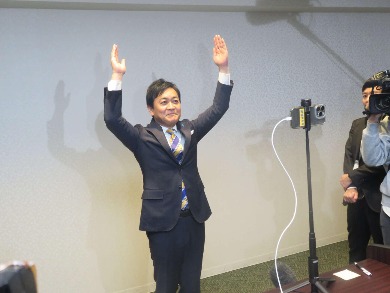 スマホで回線をつないだ地元香川の選挙事務所の支援者に向けて、万歳をする玉木雄一郎国民民主党代表
