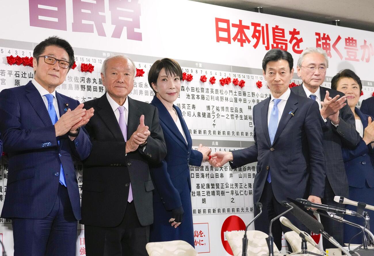 当確者の名前にバラを付ける自民党総裁の高市首相（中央左）。左から2人目は拍手する鈴木幹事長（共同）