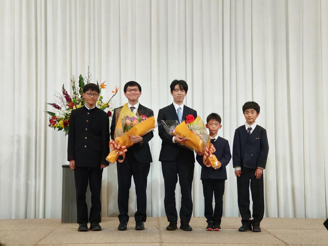 前夜祭で子どもたちから花束を贈呈された永瀬拓矢九段（左）藤井聡太王将（撮影・松浦隆司）