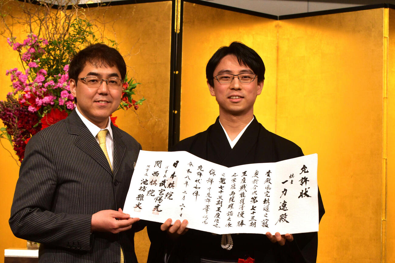 就位式で日本棋院の武宮陽光理事長（左）から允許（いんきょ）状を渡された一力遼王座（右）