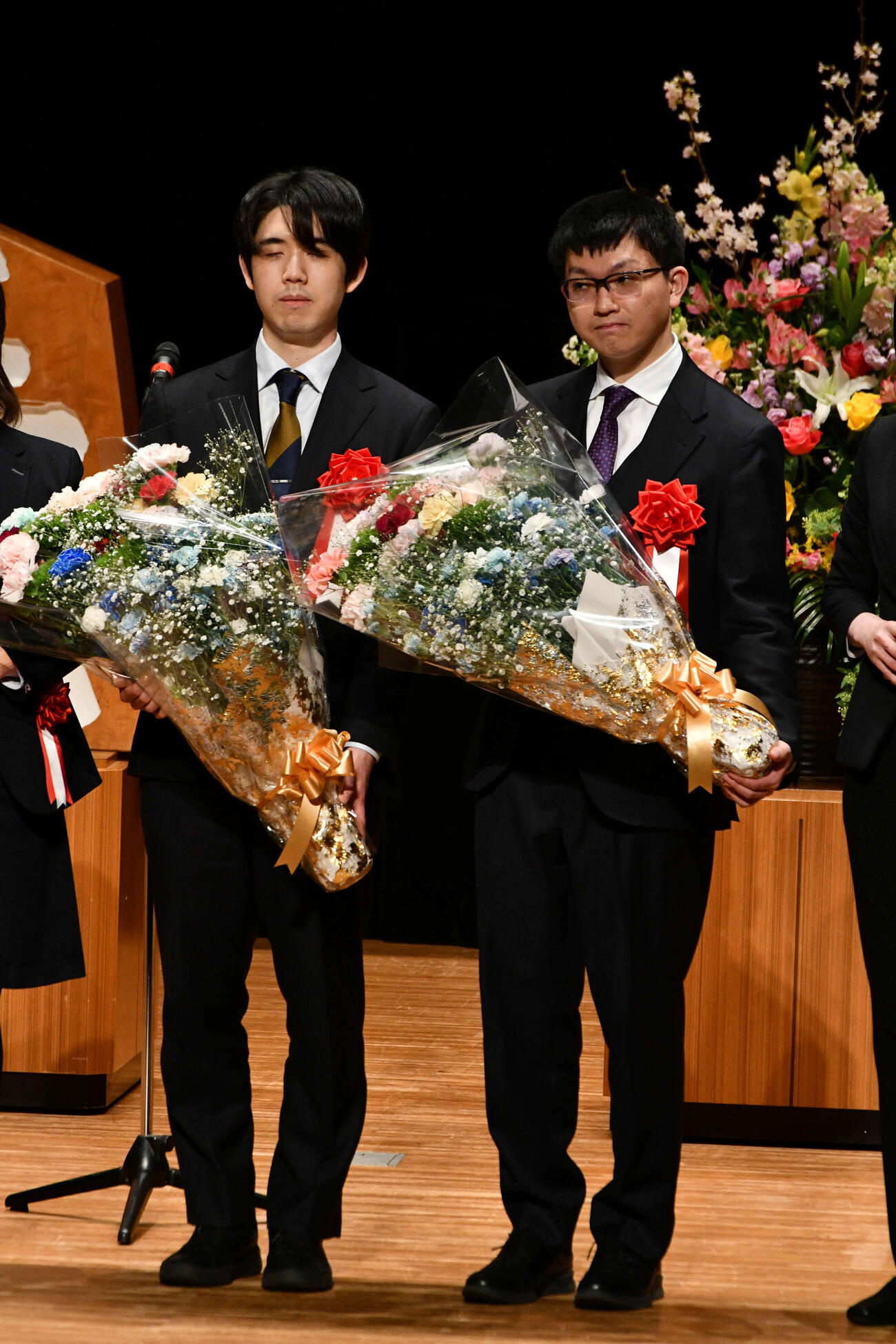 王将戦第5局の前夜祭で花束を手にする藤井聡太王将（左）と永瀬拓矢九段（右）