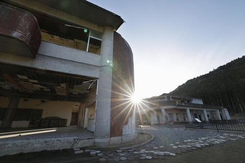 東日本大震災から15年、宮城県石巻市の旧大川小校舎の奥から昇る朝日（共同）