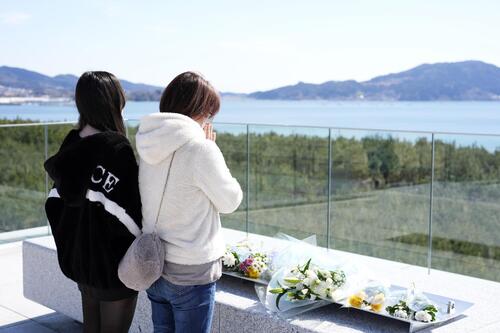 岩手県陸前高田市の防潮堤で海に向かい、手を合わせる人たち（共同）