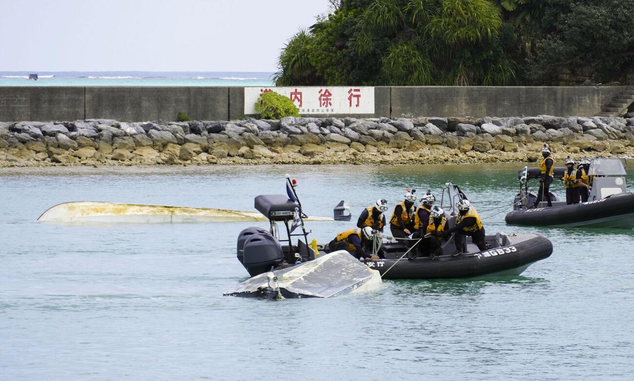 16日、転覆した船2隻をえい航する海上保安庁の職員ら（共同）