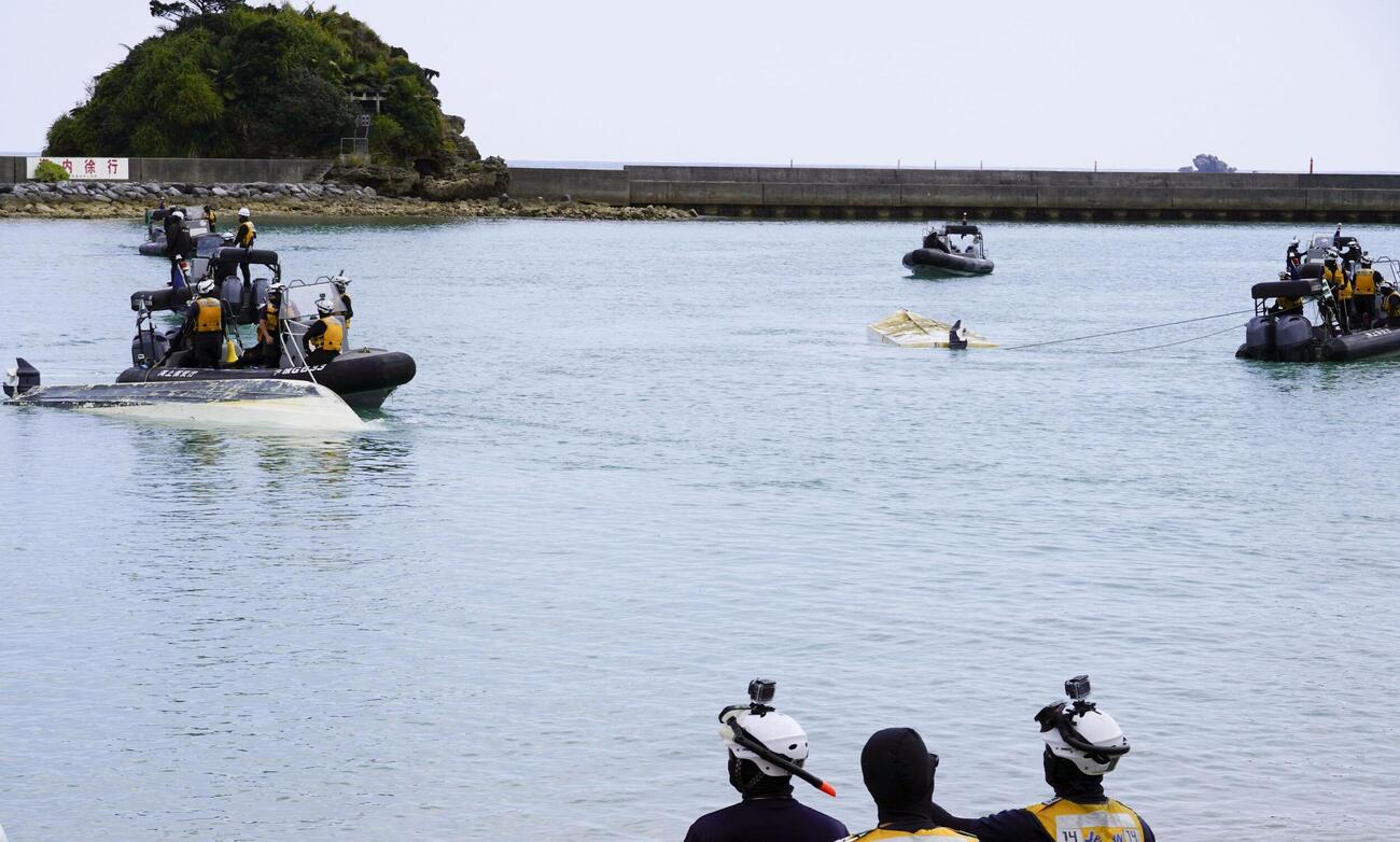 16日、転覆した船をえい航する海上保安庁の職員ら（共同）