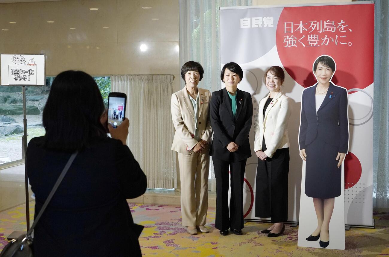 自民党大会の会場に設置された高市首相のフォトパネルで写真撮影する鈴木貴子広報本部長（中央）ら（共同）