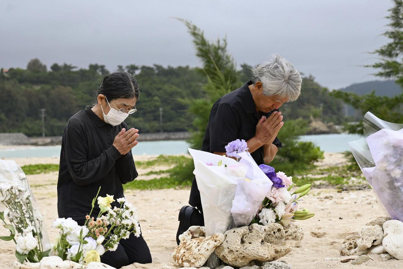転覆事故現場を臨む浜で手を合わせる「ヘリ基地反対協議会」のメンバー＝3日午前（共同）
