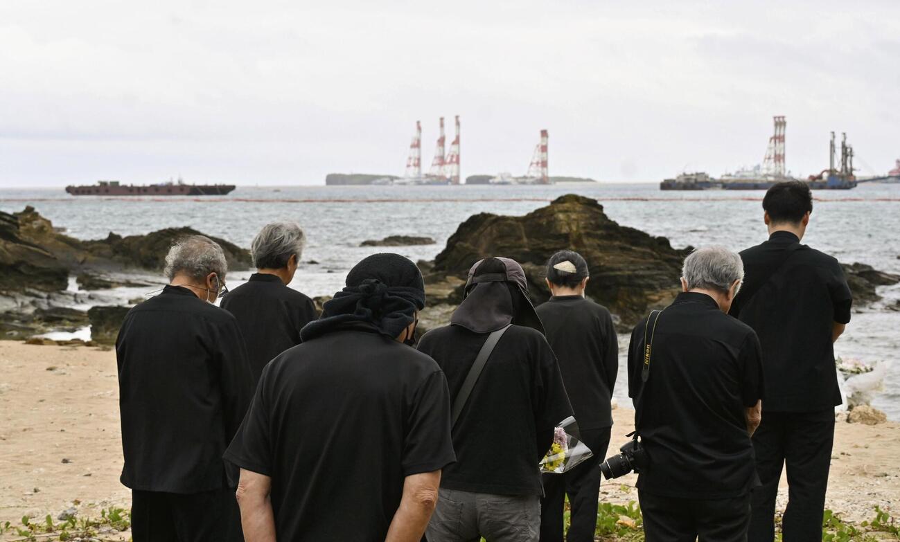 転覆事故現場を臨む浜で黙とうする「ヘリ基地反対協議会」のメンバー＝3日午前（共同）