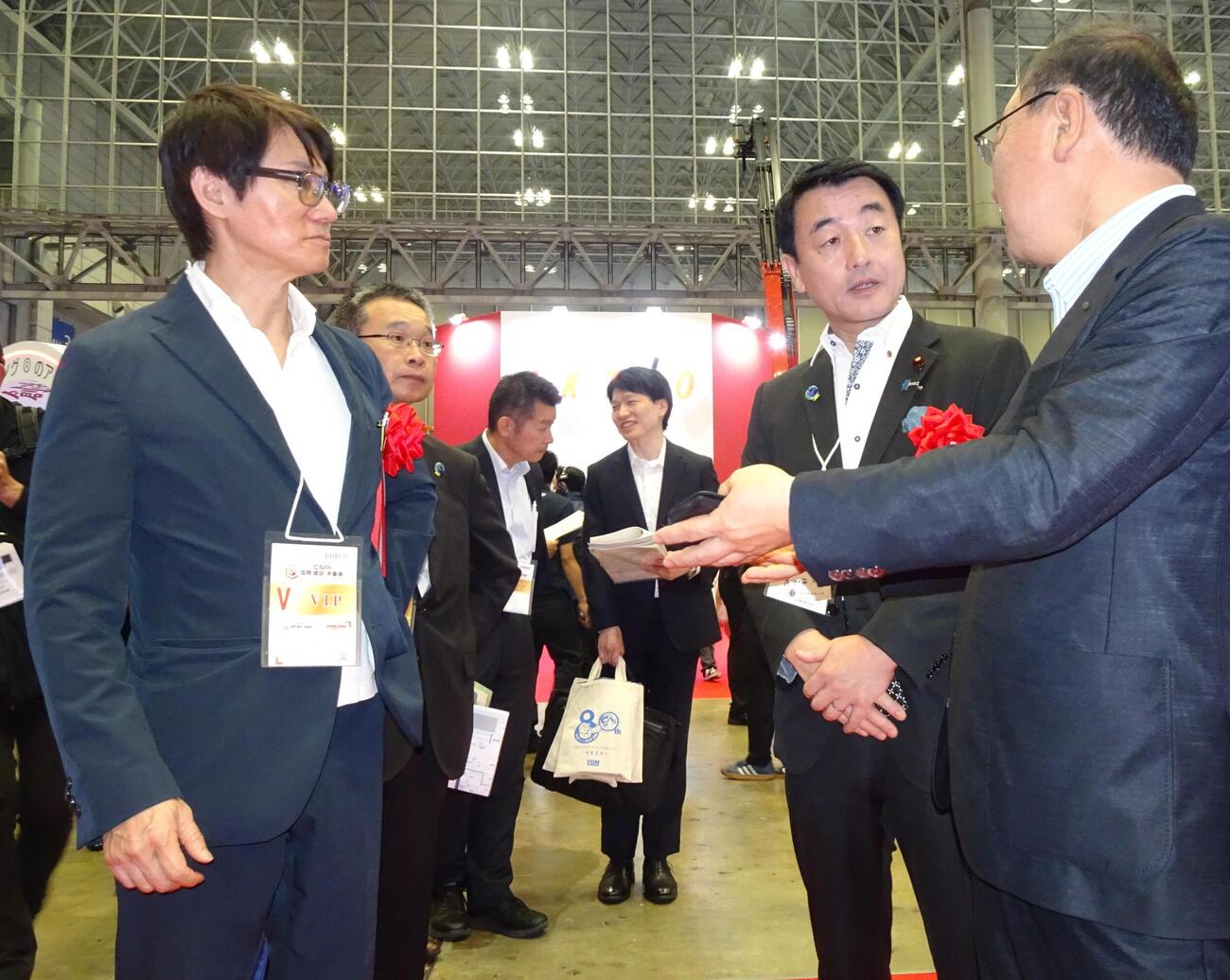 会場視察で出展社の説明を聞く谷鉄也実行委員長（左端）と佐々木紀国土交通副大臣（右から2人目）