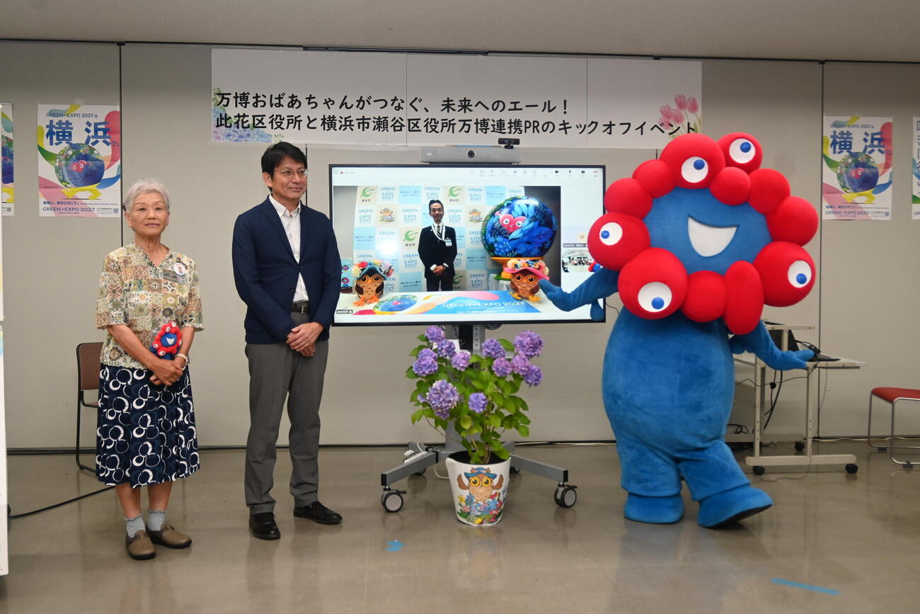 大阪市此花区役所で行われた同区と横浜市瀬谷区による万博連携PRキックオフイベントに参加した左から「万博おばあちゃん」として知られる山田外美代さん、中島政人此花区長、ミャクミャク（撮影・松浦隆司）