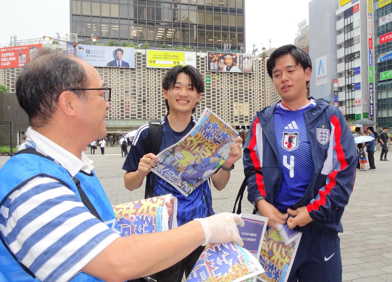 日刊スポーツ号外を手に笑顔の読者（中央）