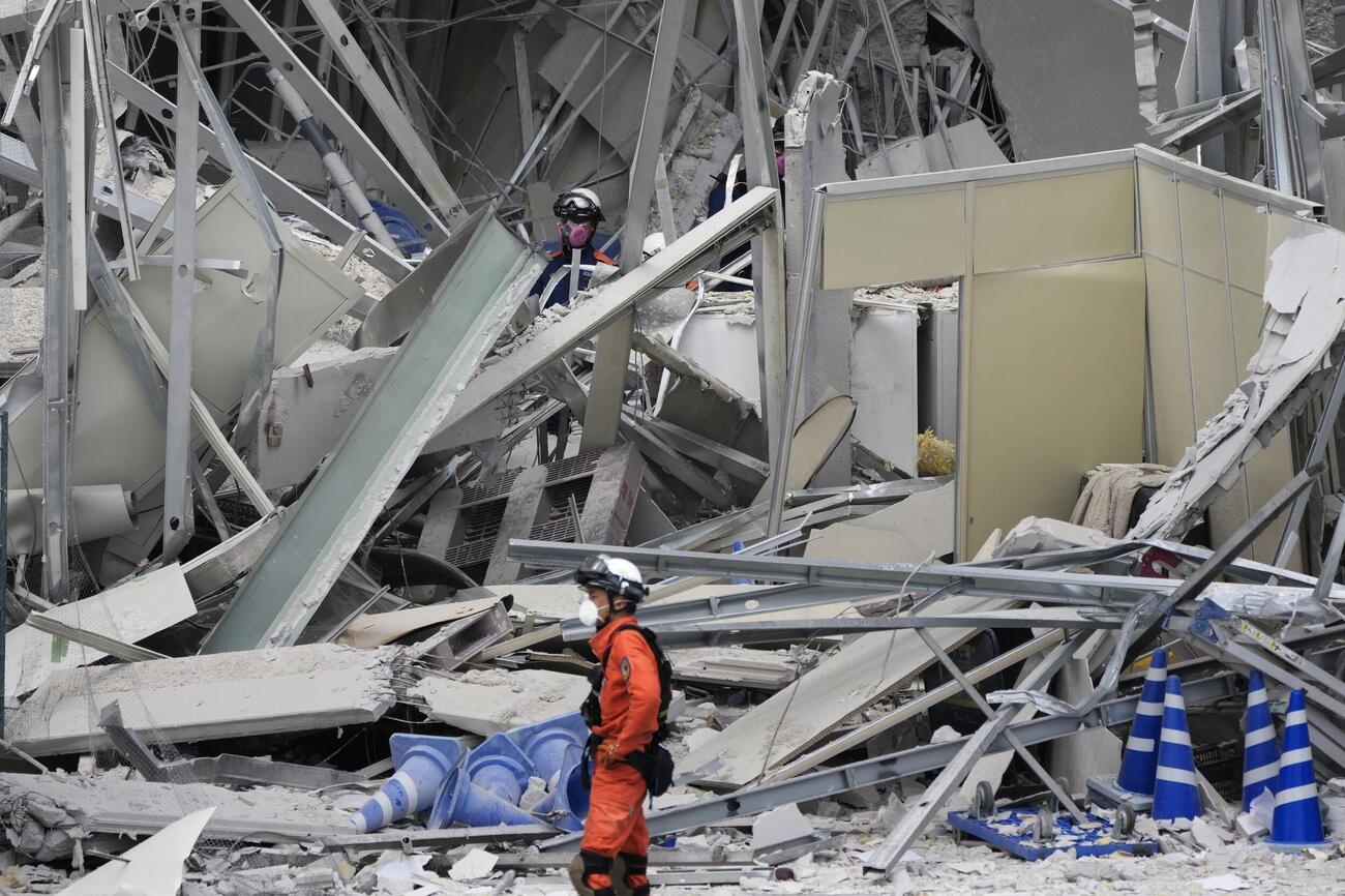 地震後に爆発が起きた「イオンモール熊本」のがれきの中で、活動する消防隊員ら（共同）
