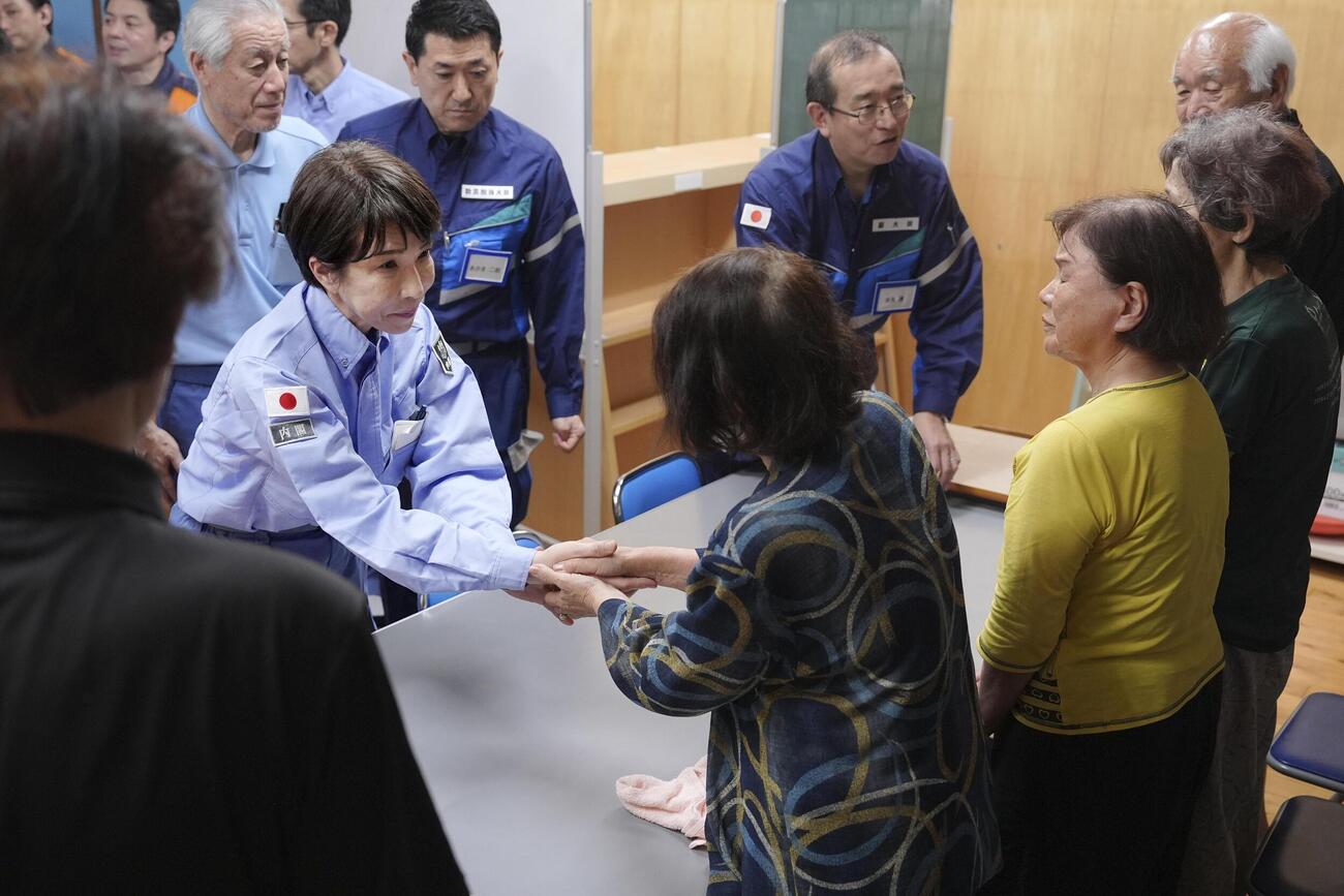 熊本県氷川町の避難所を訪れ、避難者（手前）と握手を交わす高市首相＝3日午後（代表撮影）