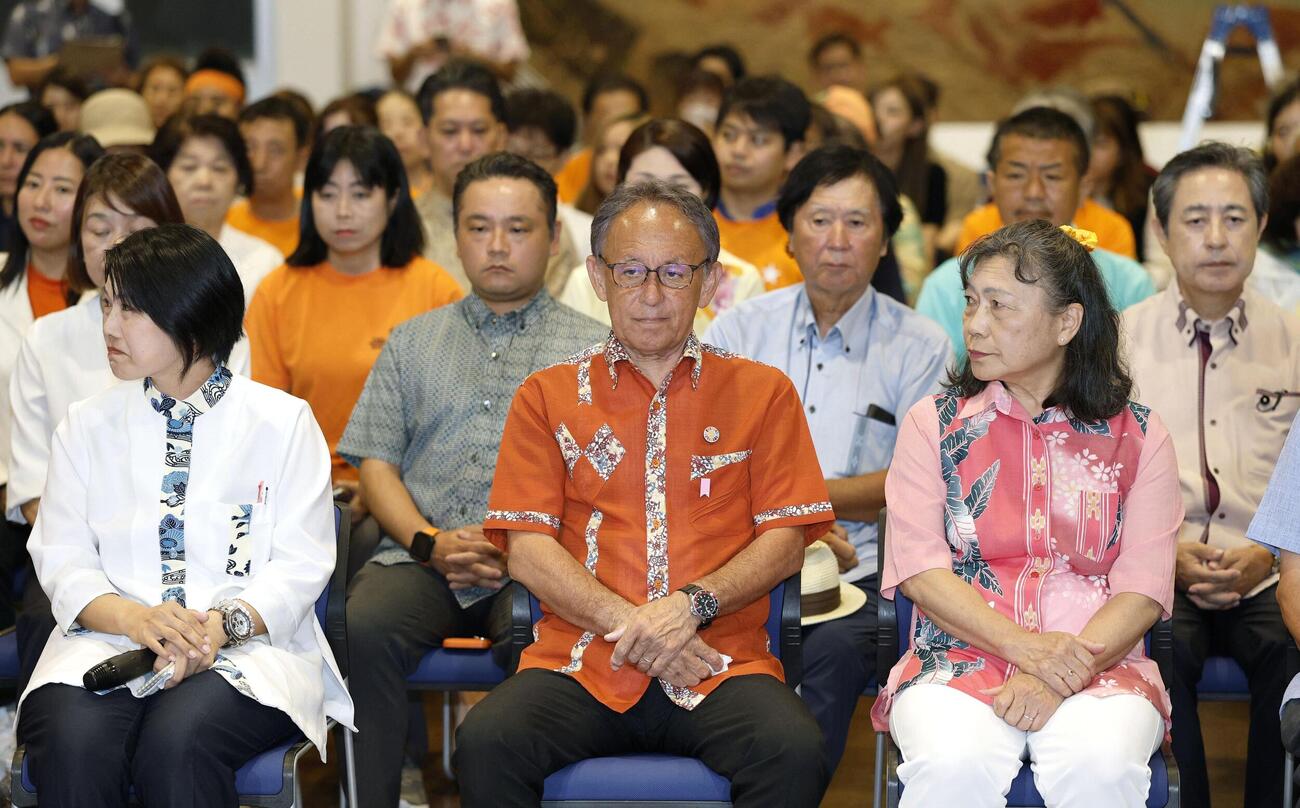 沖縄県知事選で落選が決まり、厳しい表情の玉城デニー氏（中央）＝13日夜、那覇市(共同)