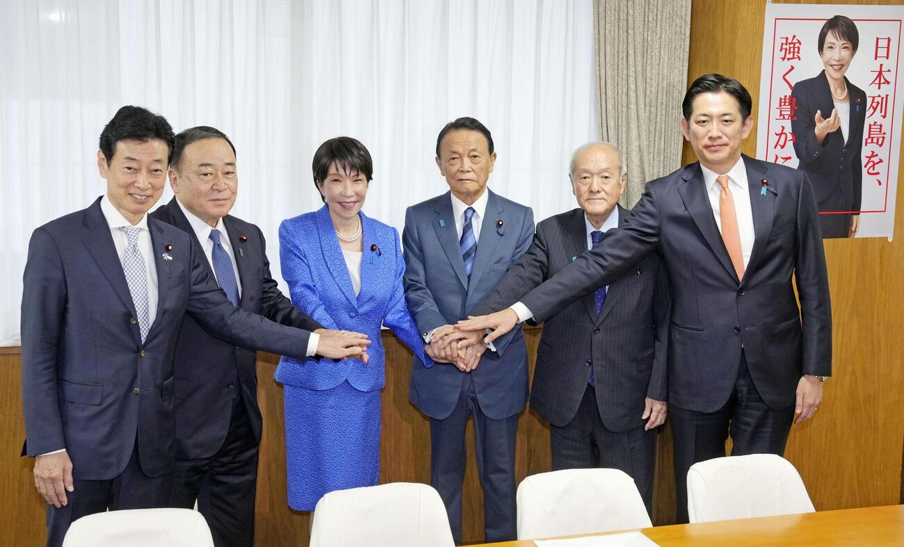 自民党の臨時総務会で手を取り合う（左から）西村選対委員長、梶山総務会長、党総裁の高市首相、麻生副総裁、鈴木幹事長、小林政調会長＝16日午前、東京・永田町の党本部（共同）