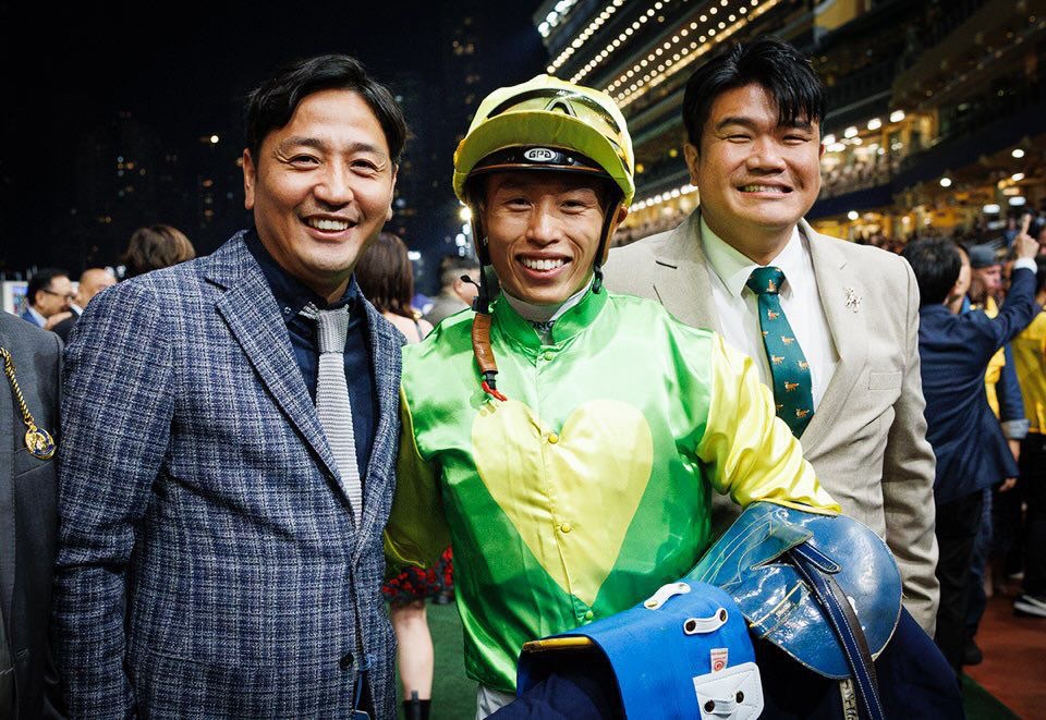 安藤裕氏（左）はホー騎手（中央）と一緒に香港スタイルの口取りに参加