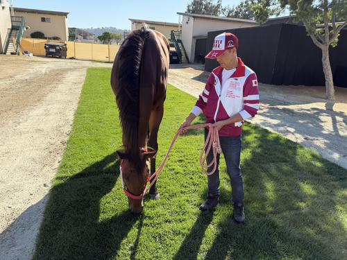 デルマー競馬場の厩舎地区で草を食むフォーエバーヤングと渋田助手（撮影・安藤裕）