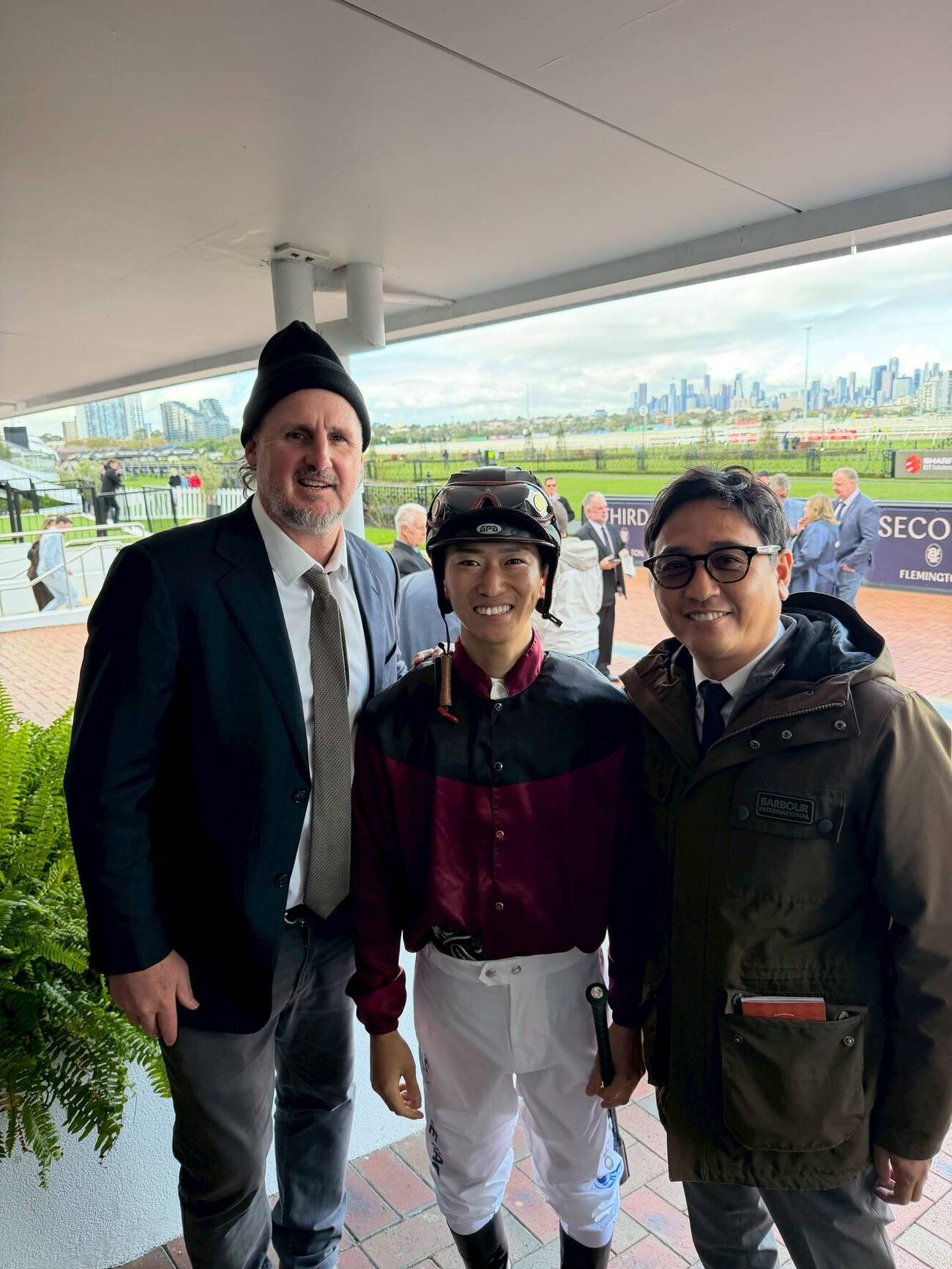 フレミントン競馬場で騎乗した菅原明良騎手、左はエージェントのトラビス氏、右は安藤裕氏