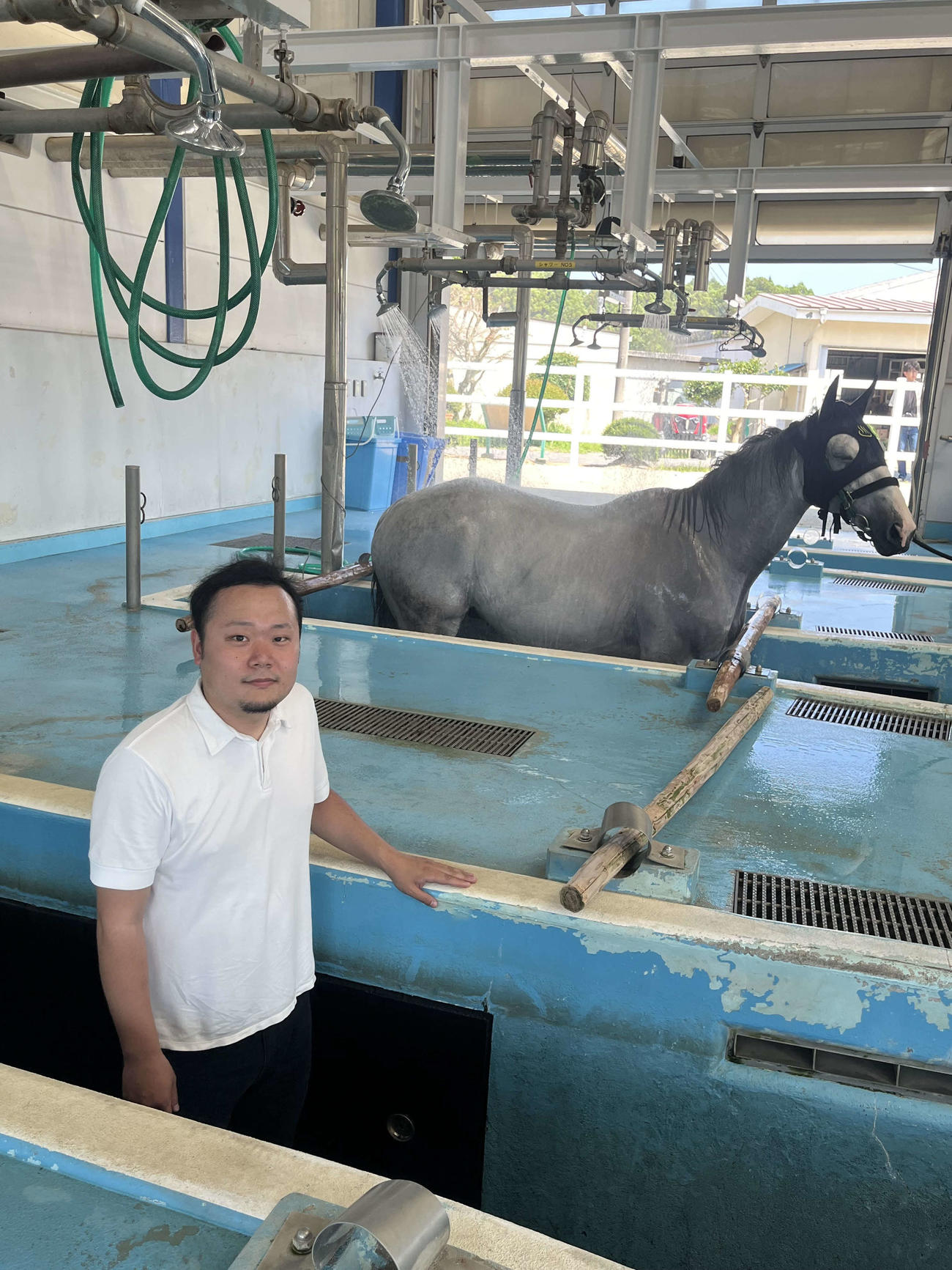競走馬専用の温泉につかるネバーリグレットと舟元祐二記者