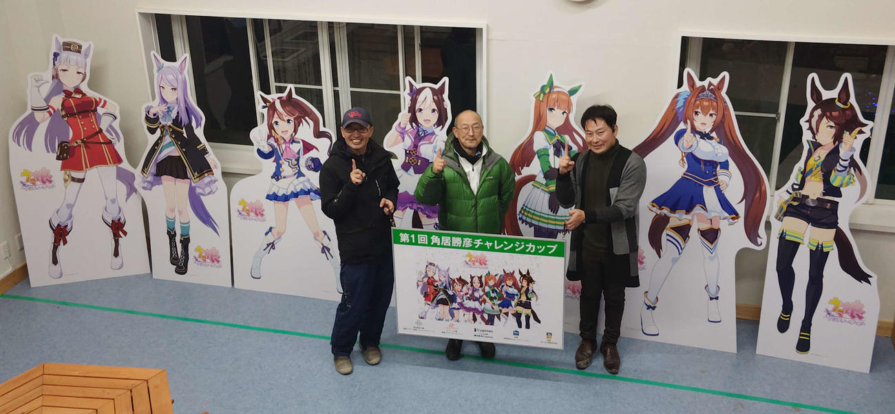 「ウマ娘　プリティーダービー」のパネルと記念撮影する、左から広田氏、角居元師、古田代表（乗馬プラザ・ホースツリー提供）