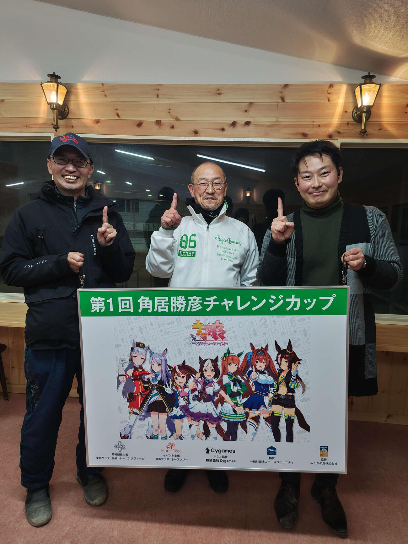 「ウマ娘　プリティーダービー」のパネルと角居元調教師（中央）左は元五輪選手の広田龍馬さん、右はホースツリー古田雅士代表（乗馬プラザ・ホースツリー提供、22年12月撮影）