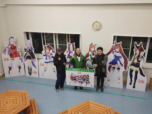 「ウマ娘　プリティーダービー」のパネルと角居元調教師（中央）左は元五輪選手の広田龍馬さん、右はホースツリー古田雅士代表（乗馬プラザ・ホースツリー提供、22年12月撮影）