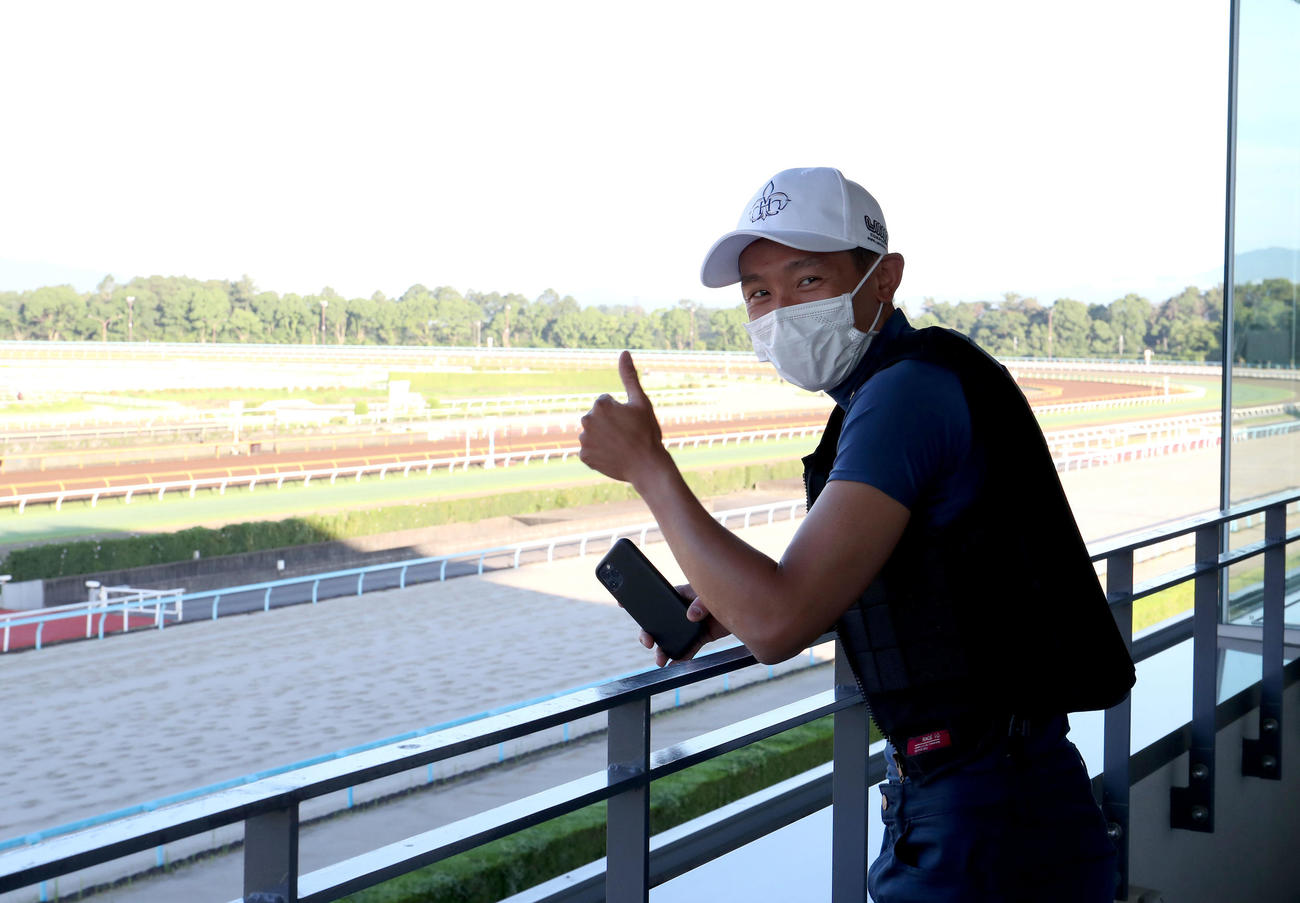 調教コースをバックにサムアップポーズするホー騎手（撮影・白石智彦）