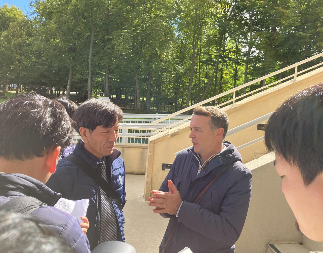 29日、シャンティイ競馬場で取材に応じたF・グラファール師（右から2人目）
