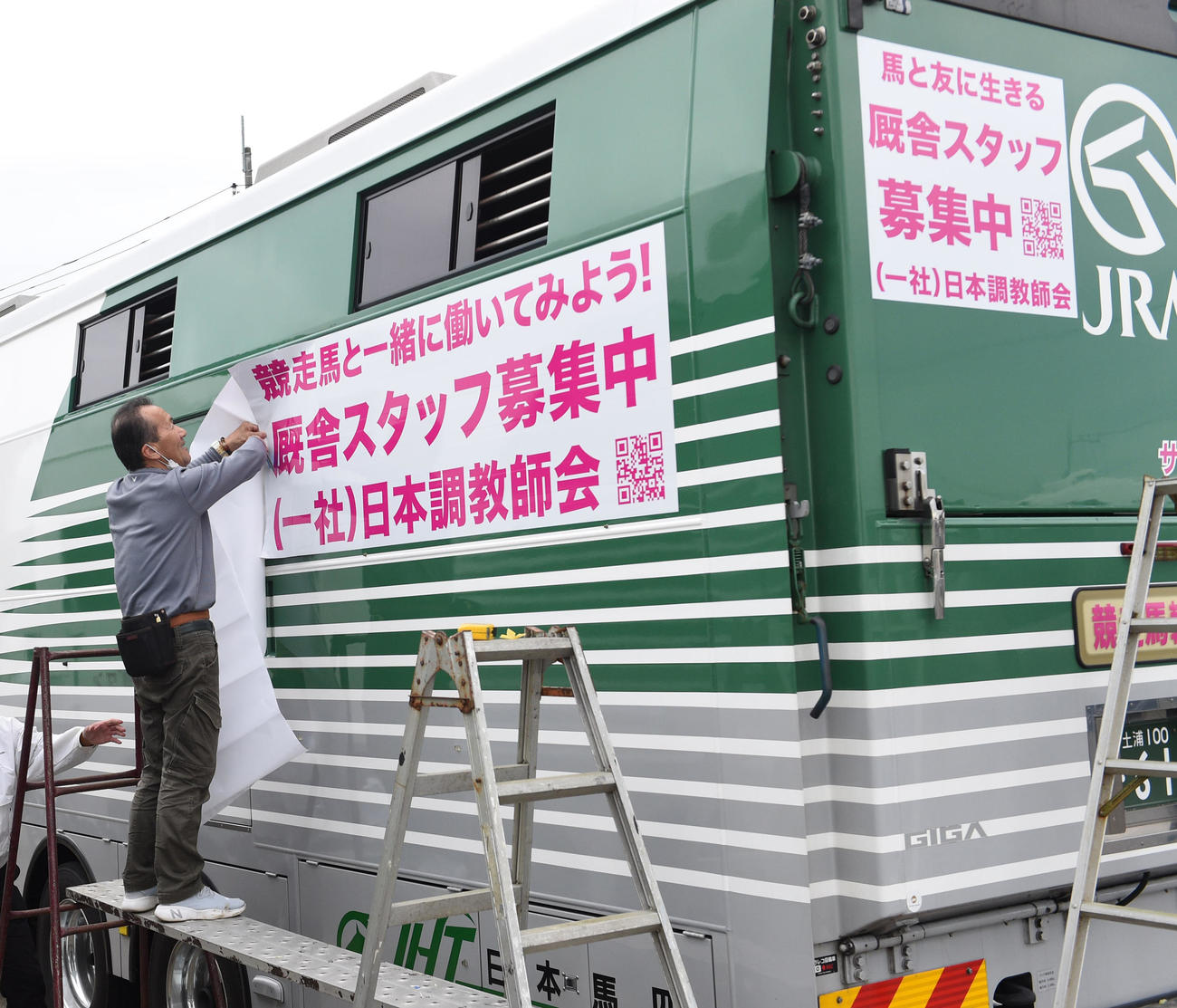 馬運車に「厩舎スタッフ募集中」をラッピングする関係者（撮影・柴田隆二）
