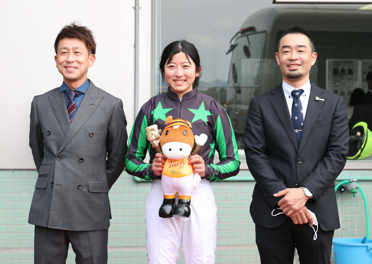 22年3月、JRA初勝利を挙げ記念撮影する左から、父の今村康成調教助手、今村聖奈騎手、師匠の寺島師