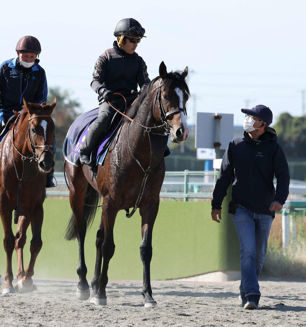 調教を終えて馬場を出るダノンベルーガと、スタッフから話を聞く堀宣行師（右）（撮影・丹羽敏通）