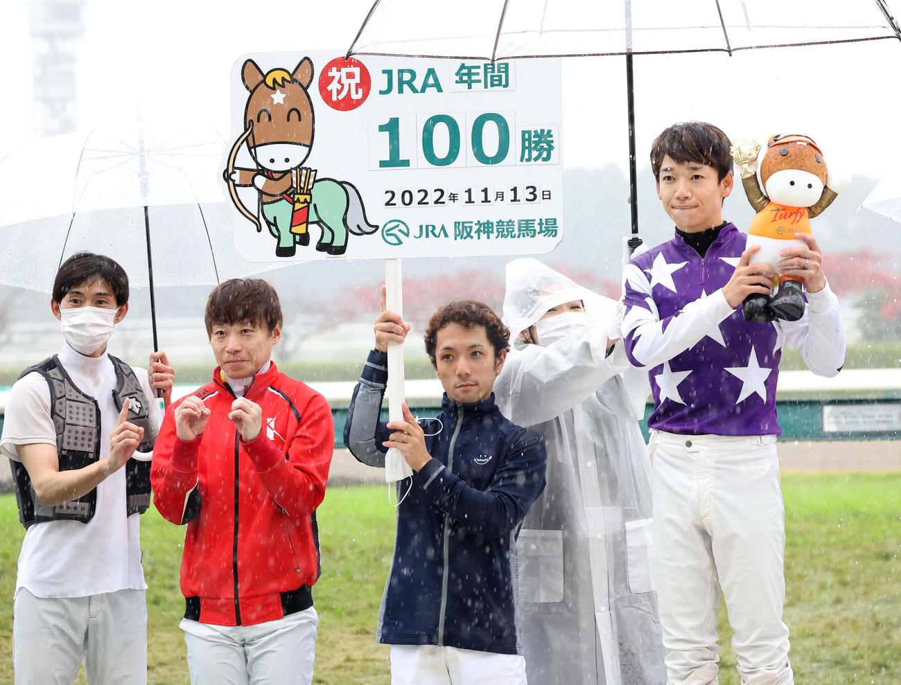 JRA年間100勝を達成した松山騎手（右）と、左から100勝ポーズを取る藤岡康騎手、池添騎手、ボードを持つ藤懸騎手（撮影・白石智彦）
