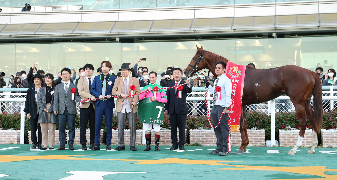 京都2歳Sを制したグリューネグリーンと口取りに並ぶM・デムーロ騎手（右から3人目）