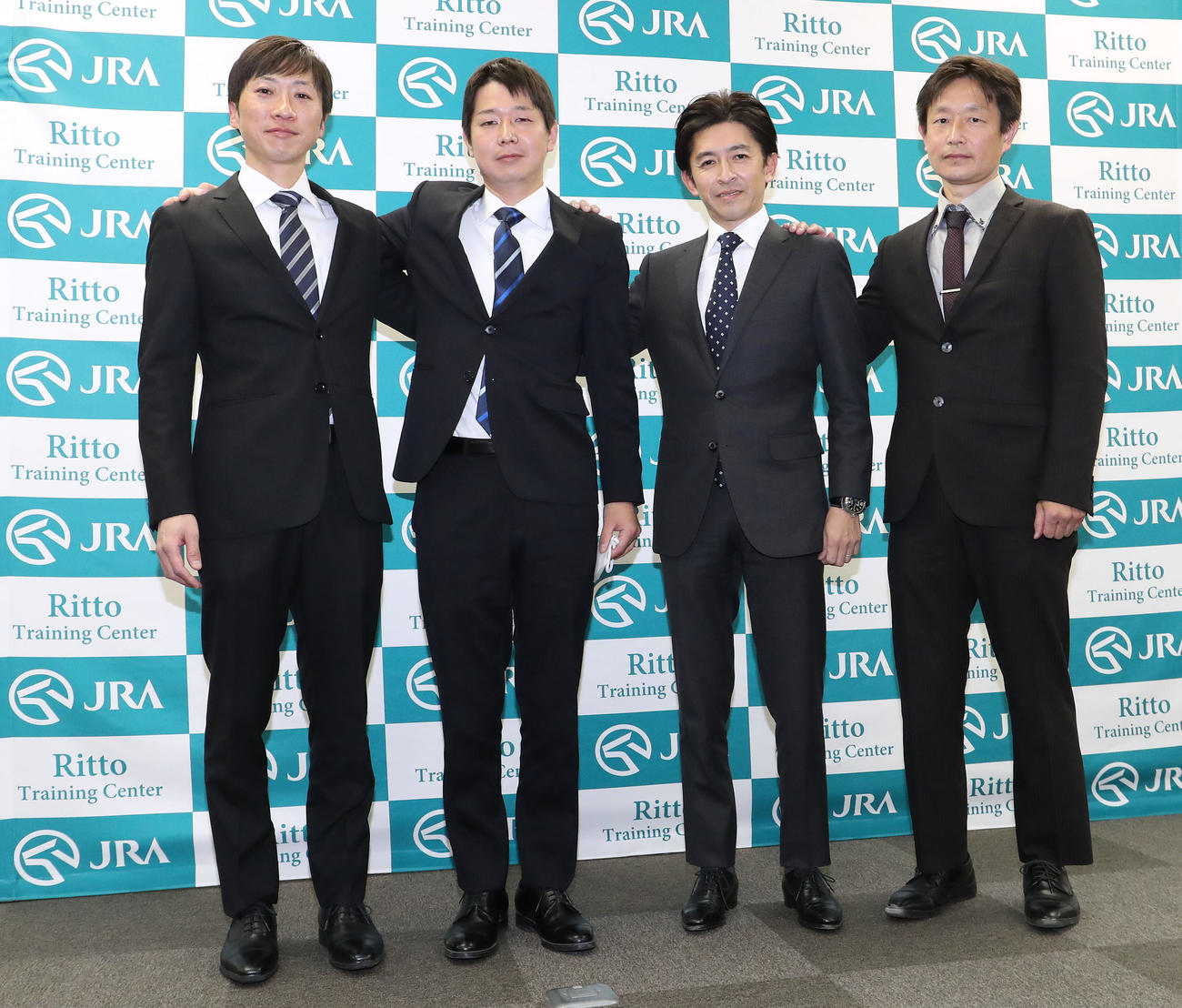 肩を組んで記念撮影に納まる左から、小椋助手、河嶋助手、福永騎手、藤野助手（撮影・白石智彦）