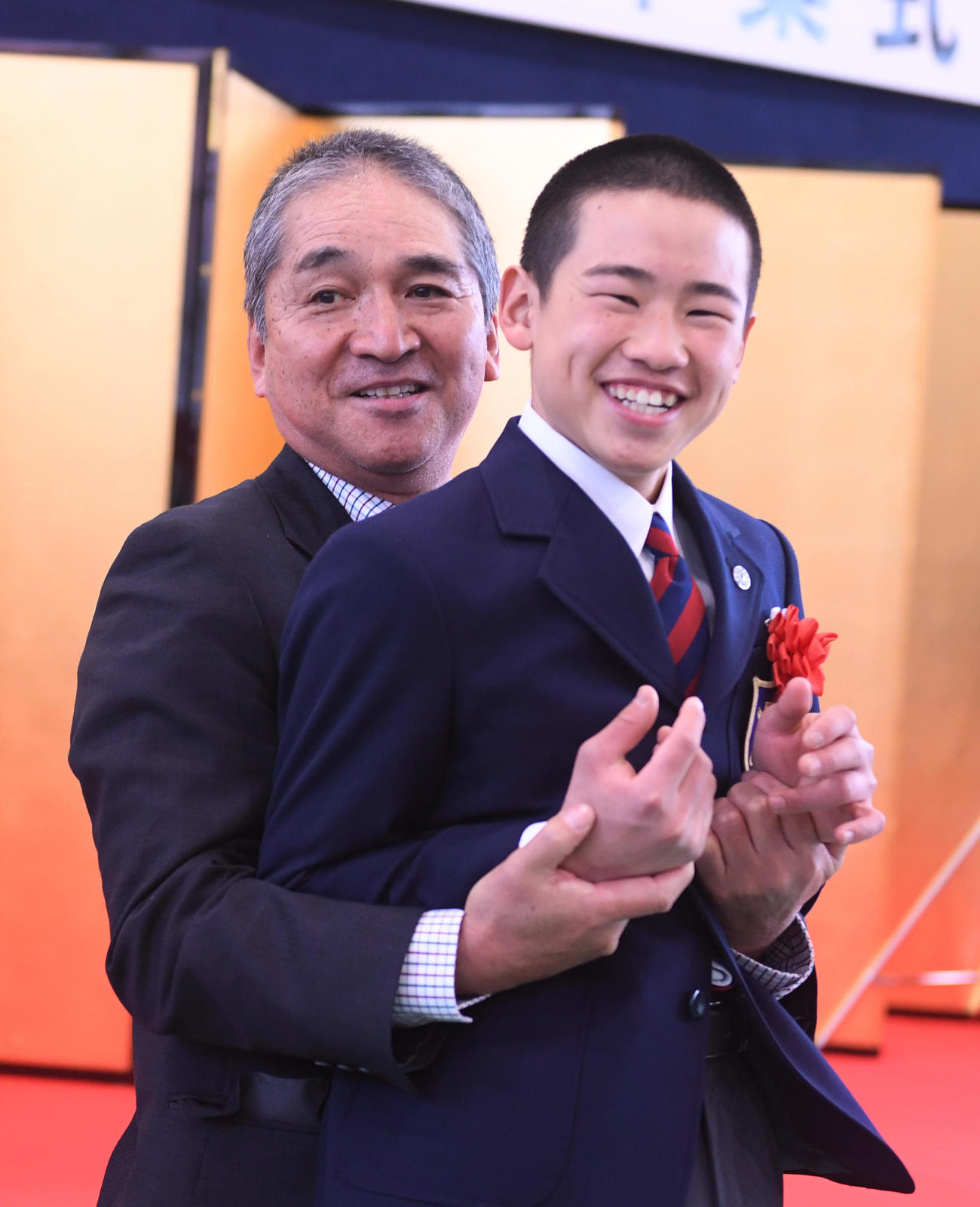 卒業式で、小桧山悟調教師（左）から抱き上げられる佐藤翔馬騎手（撮影・柴田隆二）