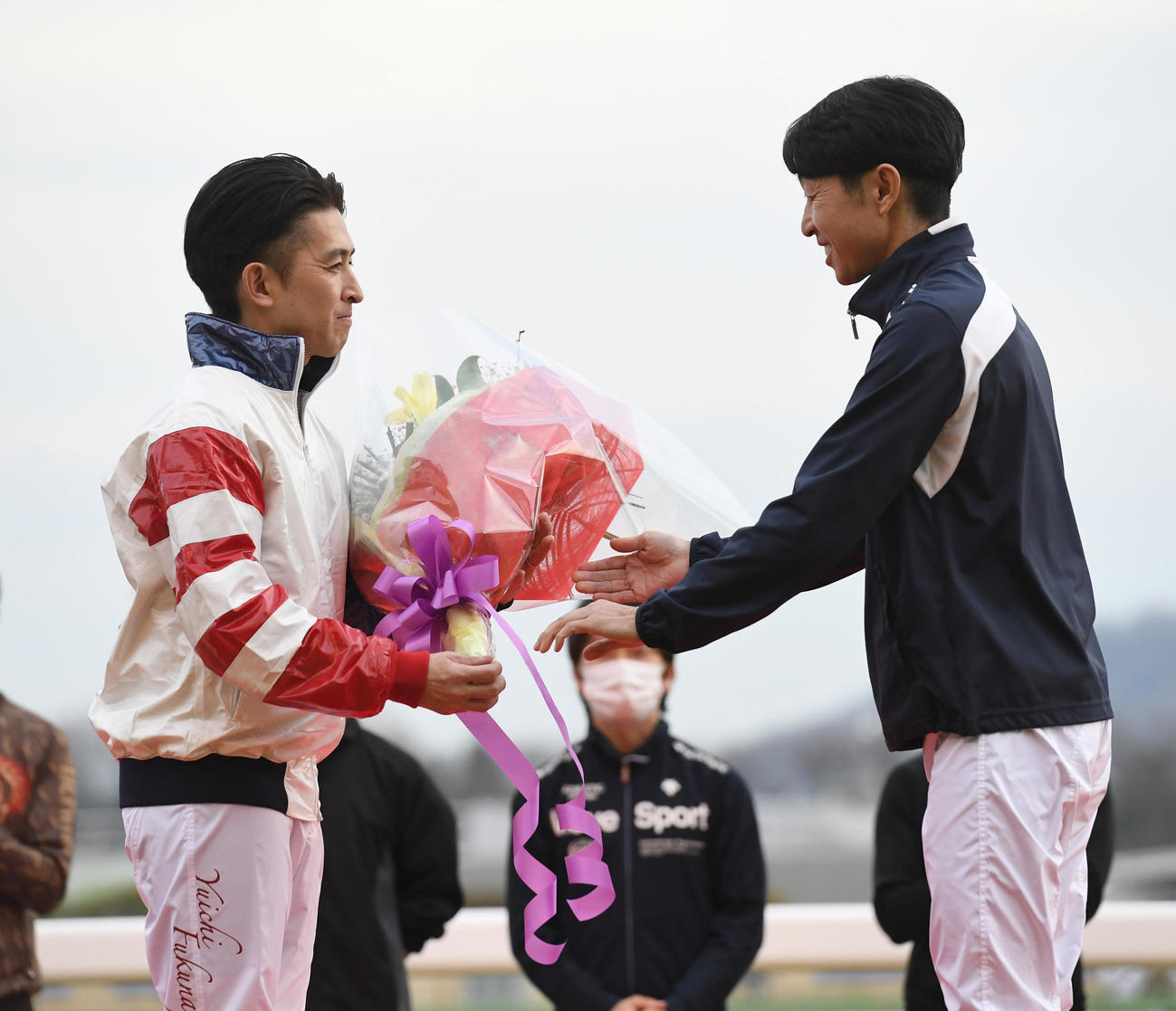 JRA最終騎乗後インタビューで、武豊騎手から花束を贈られた福永騎手（左）（撮影・柴田隆二）