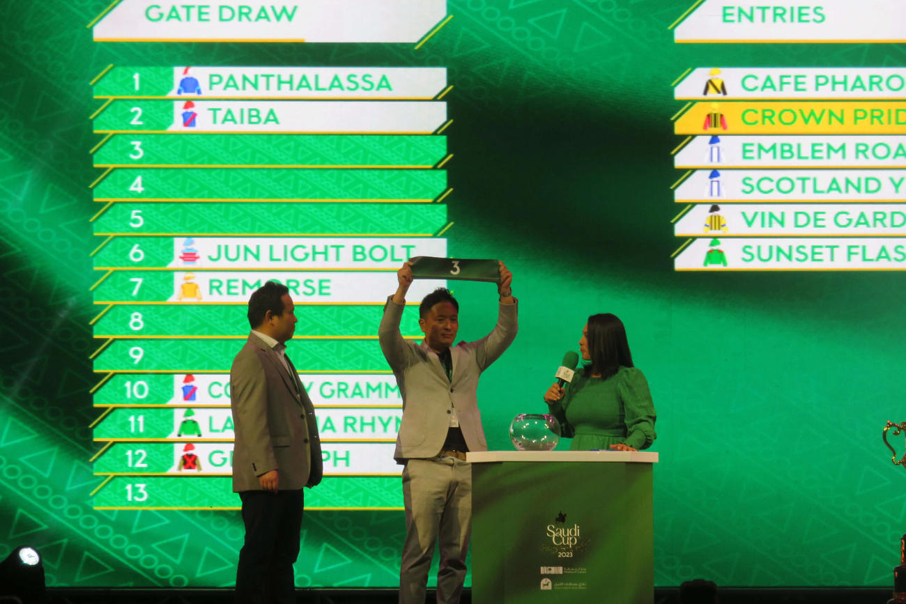 サウジカップの公開枠順抽選会で3番を引いたクラウンプライドの新谷師（中央）
