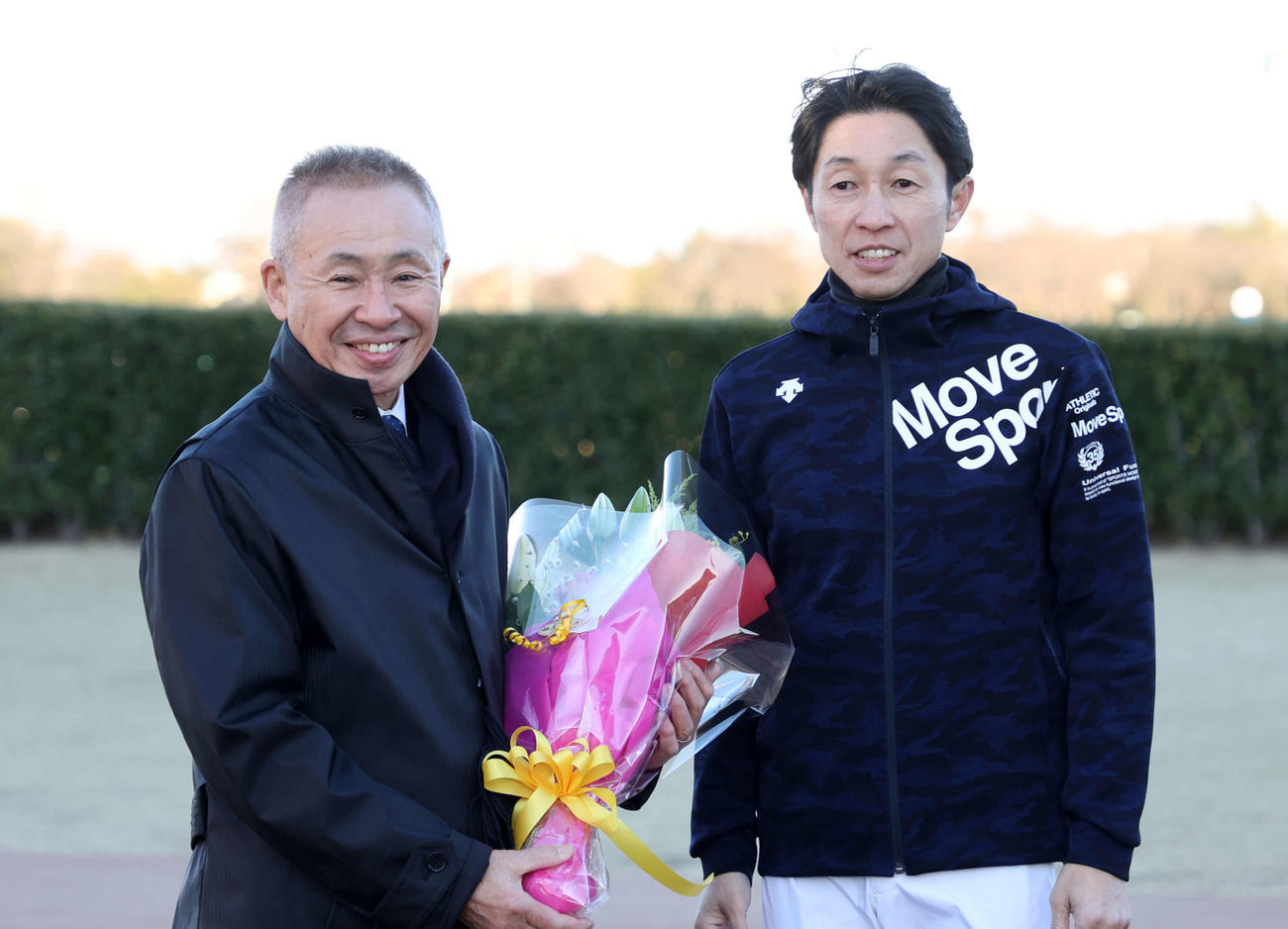 武豊騎手（右）から花束を受け取り笑顔を見せる大江原調教師（撮影・鈴木正人）