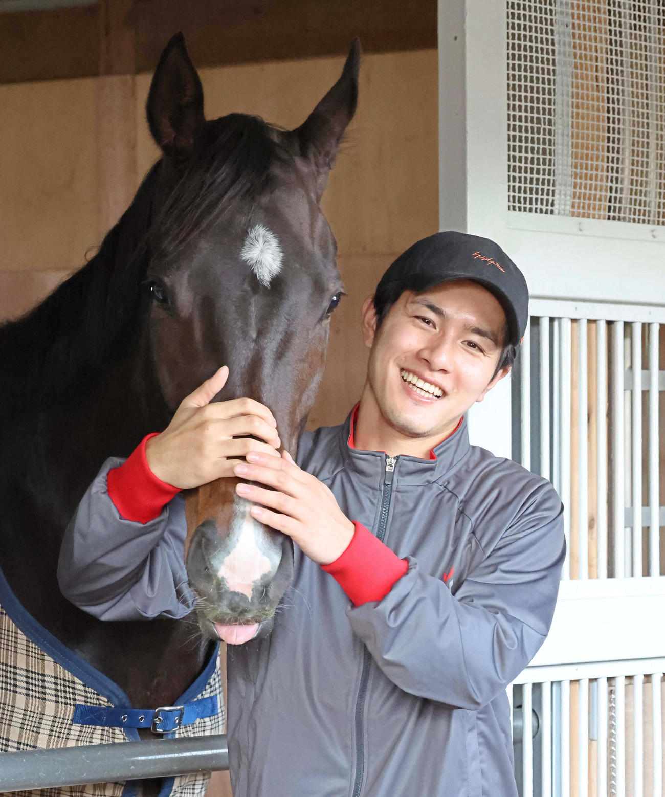 馬房で管理馬をなでる新規開業した上原佑師（撮影・丹羽敏通）