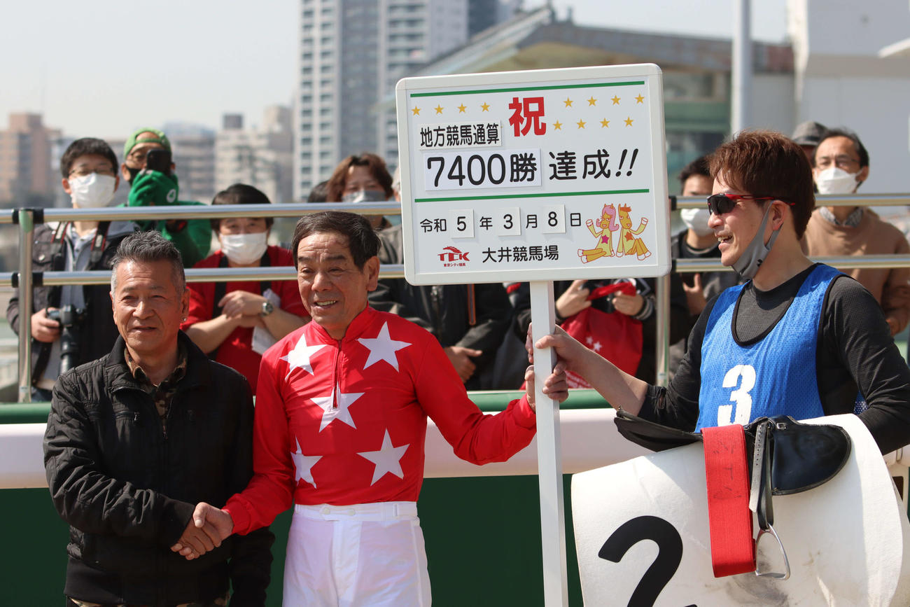地方競馬通算7400勝を達成した大井の的場文男騎手（中央）は、集まったファンの前で記念撮影