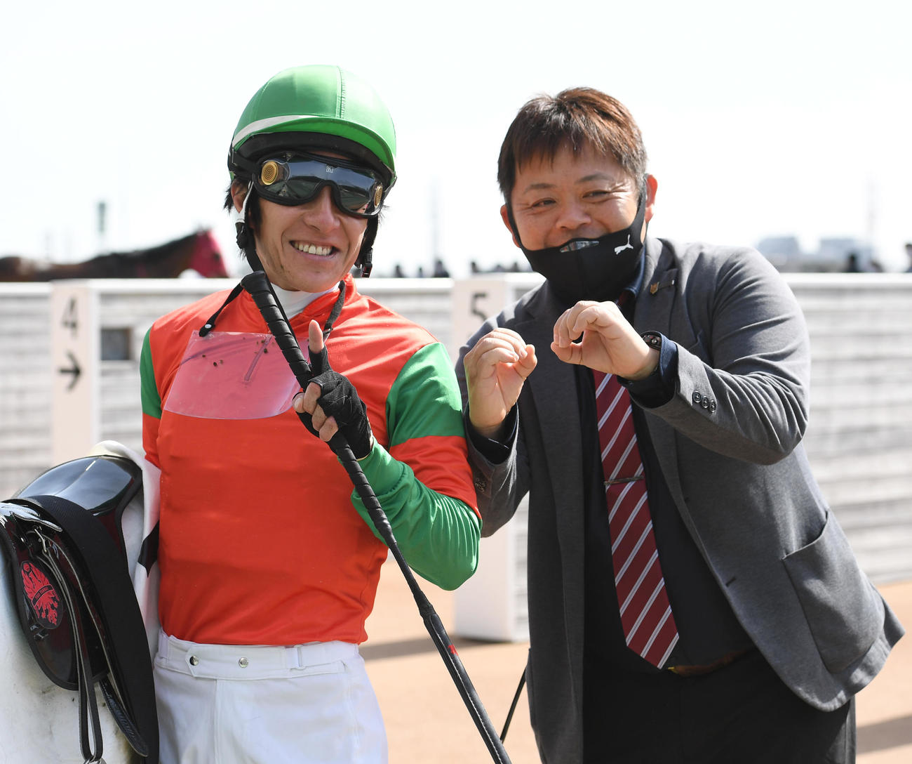 中山7Rで通算1万回騎乗を達成した丹内騎手（左）は青木調教師とパフォーマンスする（撮影・柴田隆二）