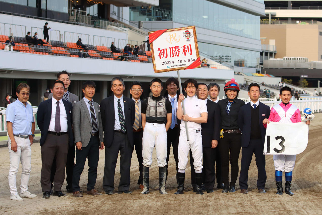 デビュー初勝利を挙げた佐藤翔馬騎手（右端）と記念撮影に納まる父の佐藤博紀調教師（右から2人目）